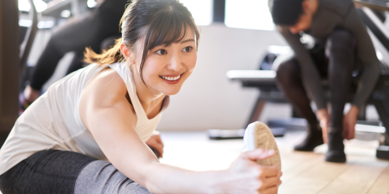 パーソナルジムで笑顔でストレッチをする女性